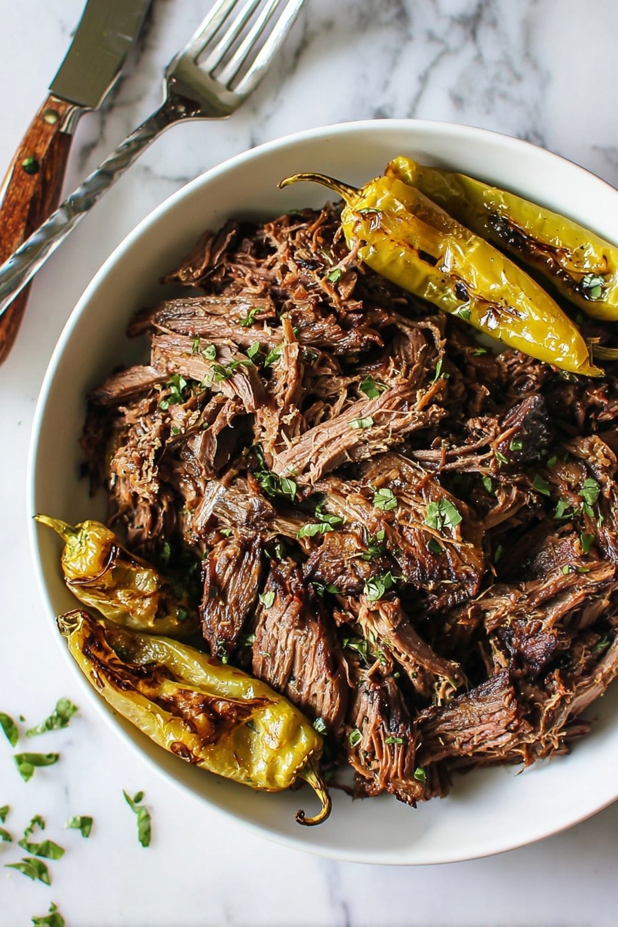 Mississippi Pot Roast - The image shows a white bowl filled with shredded dark brown meat scattered with small green herb pieces on top. On one side of the bowl, there are four charred yellow peppers with a slightly wrinkled texture. The bowl rests on a white marbled surface with a silver fork with a wooden handle placed near the top right edge. The meat looks tender and juicy, with strands clumped together, and the herbs add a fresh touch. photo taken with an iphone --ar 2:3 --v 7