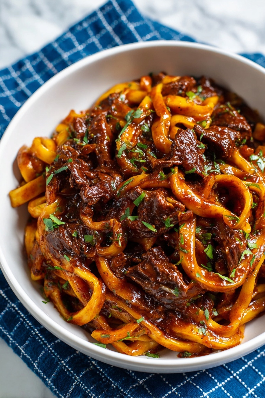 A white bowl is filled with wide, flat noodles coated in a rich, dark reddish-brown sauce. Mixed in are tender pieces of dark brown meat and chopped green herbs, giving a splash of color. The noodles have a glossy, slightly thick texture with some curled ends, and the sauce looks thick and hearty. The bowl sits on a blue cloth with a white grid pattern, all placed on a white marbled surface. photo taken with an iphone --ar 2:3 --v 7