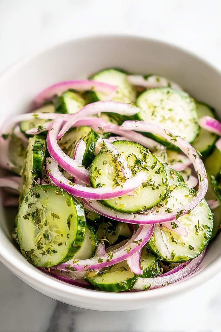 A white bowl holds a fresh salad made up of two main layers. The bottom layer is made of round cucumber slices with green edges and pale green centers, sprinkled with small green herb flakes. On top, there are thin slices of purple and white onions scattered evenly around the cucumbers, also coated lightly with the herb dressing that gives a slight shine to the vegetables. The background surface shows a white marbled texture. Photo taken with an iphone --ar 2:3 --v 7
