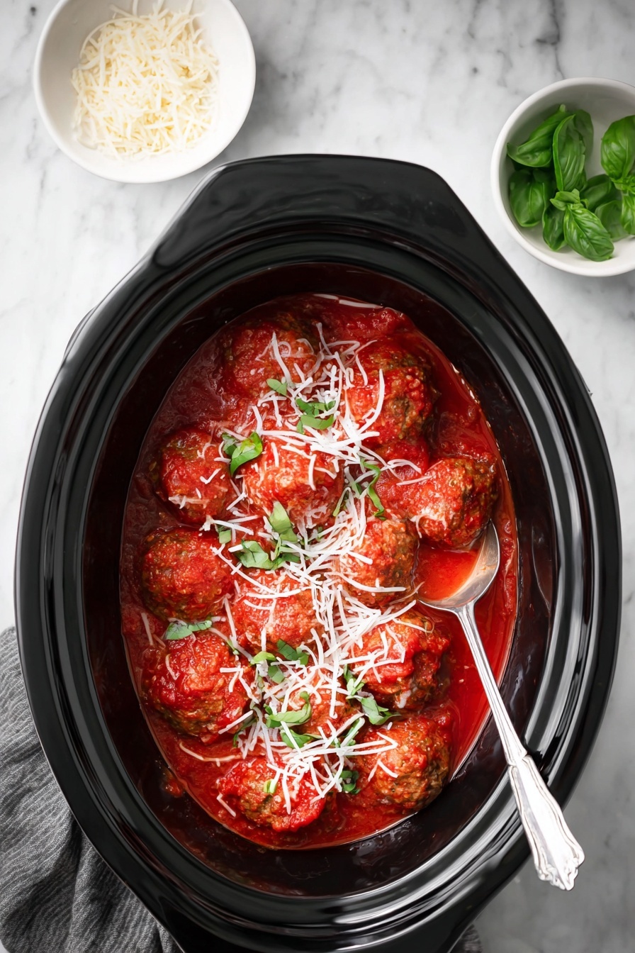 The image shows a black oval slow cooker filled with several medium-sized meatballs covered in bright red tomato sauce. The meatballs are topped with a layer of finely shredded white cheese and small pieces of green basil leaves scattered on top. A silver spoon rests inside the cooker on the right side, partially submerged in the sauce. The cooker is set on a white marbled surface with two small white bowls nearby, one containing fresh basil leaves and the other shredded cheese. Photo taken with an iphone --ar 2:3 --v 7