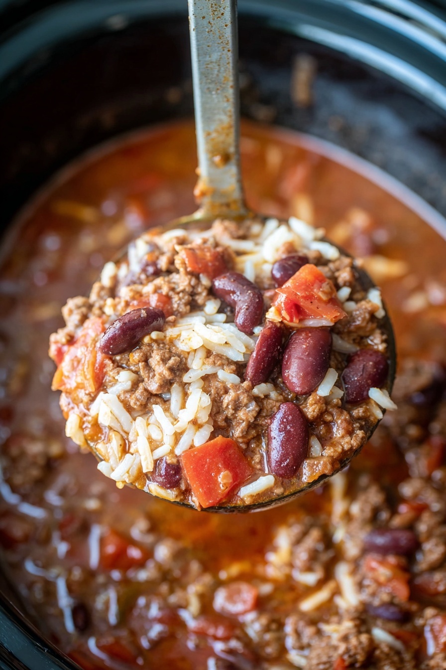 A white bowl filled with three main layers: the bottom layer has a thick red-brown soup base mixed with beans, ground meat, and diced onions; the middle layer shows white rice grains scattered throughout the soup; the top layer includes melted yellow cheese and a small dollop of white sour cream at the center. A spoon lifts a mix of the soup, rice, ground meat, beans, and tomato chunks above the bowl. The bowl sits on a white marbled surface, and a colorful cloth with yellow and red stripes is softly blurred in the background. Photo taken with an iphone --ar 2:3 --v 7