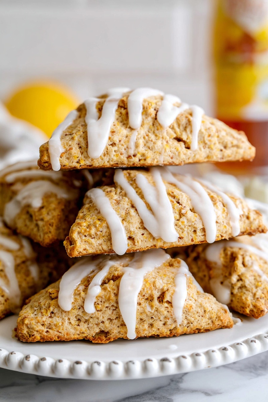 A stack of five golden brown scones shaped like triangles is arranged close together on a white plate with a beaded edge. Each scone is topped with a white, smooth icing drizzled in thin, uneven lines that run over the edges and down the sides. The scones have a crumbly, textured surface with small cracks, giving them a fresh baked look. The background shows a white marbled texture, and there is a bottle with a yellow label blurred in the distance. photo taken with an iphone --ar 2:3 --v 7