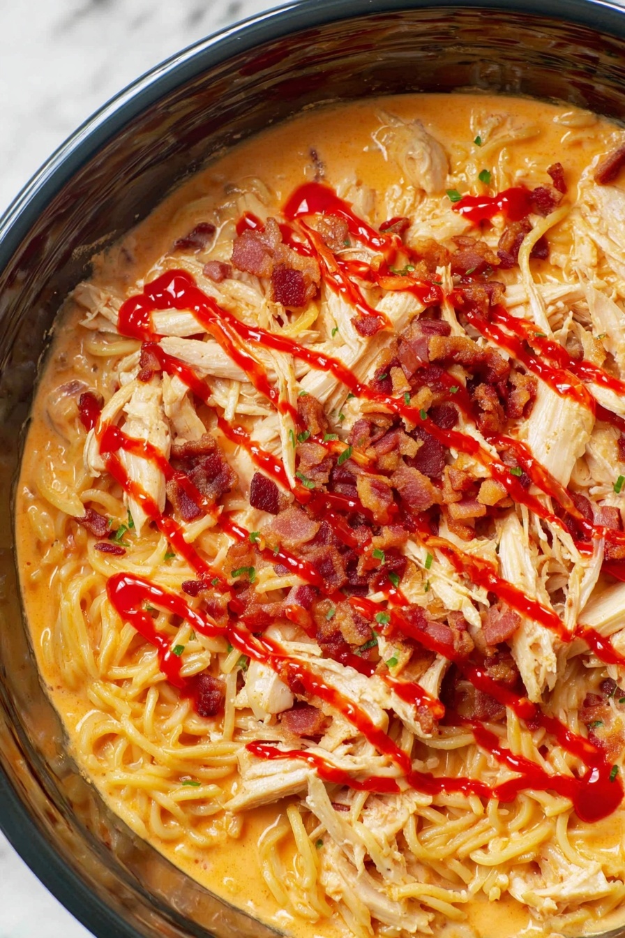 The image shows a close-up of a creamy noodle dish inside a dark pot, with three visible layers: at the bottom, a layer of cooked noodles coated in a smooth, light orange sauce; spread evenly on top are pieces of shredded white chicken; the top layer has scattered strips of crispy bacon and thin lines of bright red sauce drizzled across the whole dish, adding a vivid contrast. The background is a white marbled texture, photo taken with an iphone --ar 2:3 --v 7