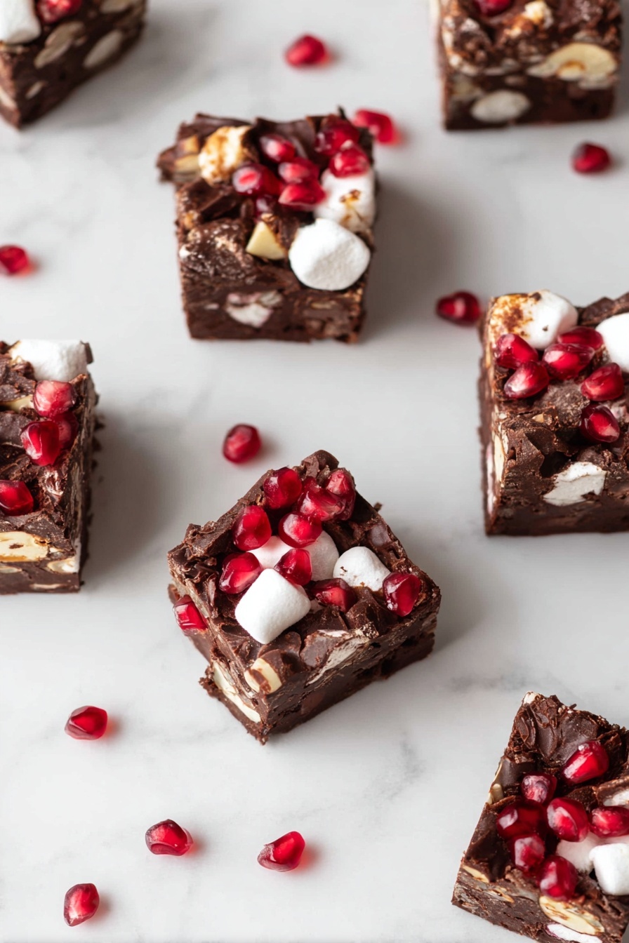 A rectangular chocolate dessert with visible chunks of white marshmallows and nuts is placed on white parchment paper on a dark wooden surface. The top is covered with bright red pomegranate seeds, adding a pop of color and texture. Two thick pieces are cut from the main block, showing the rough, uneven edges of the chocolate mixture with embedded marshmallows and nuts. In the background, there is a small wrapped plant with green leaves and a black-and-white plaid cloth around its pot, set against a white marbled texture. Photo taken with an iphone --ar 2:3 --v 7