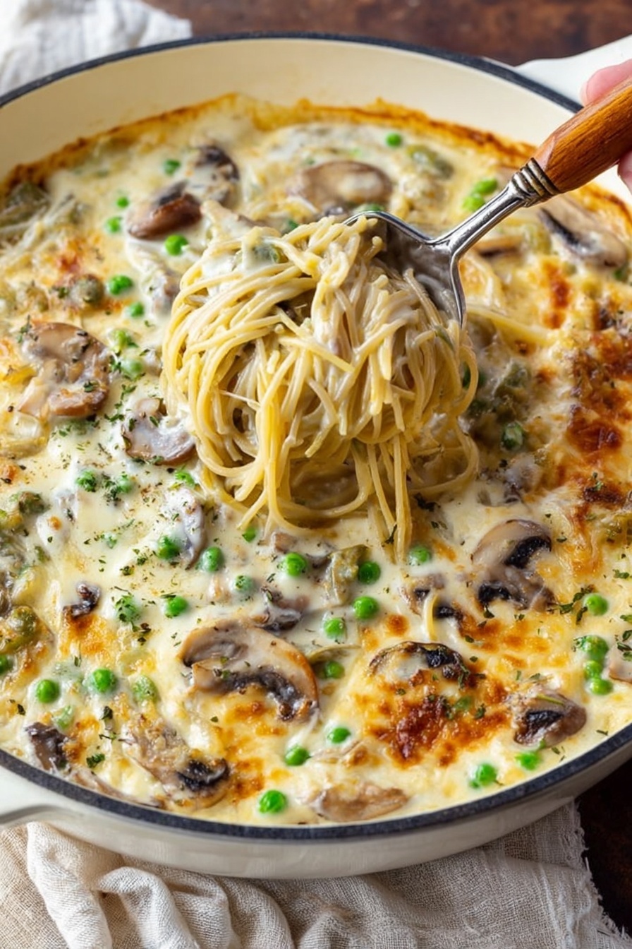The image shows a creamy pasta dish in a white pan with a lot of melted cheese on top, browned in spots. There are layers of spaghetti noodles mixed with mushrooms and green peas, all covered in a thick, white sauce. A woman’s hand is holding a silver serving spoon with a wood handle, lifting some spaghetti and mushrooms from the center of the pan, revealing the tangled noodles under the cheesy top layer. The pan sits on a black marbled surface with a blue and white cloth nearby. photo taken with an iphone --ar 2:3 --v 7