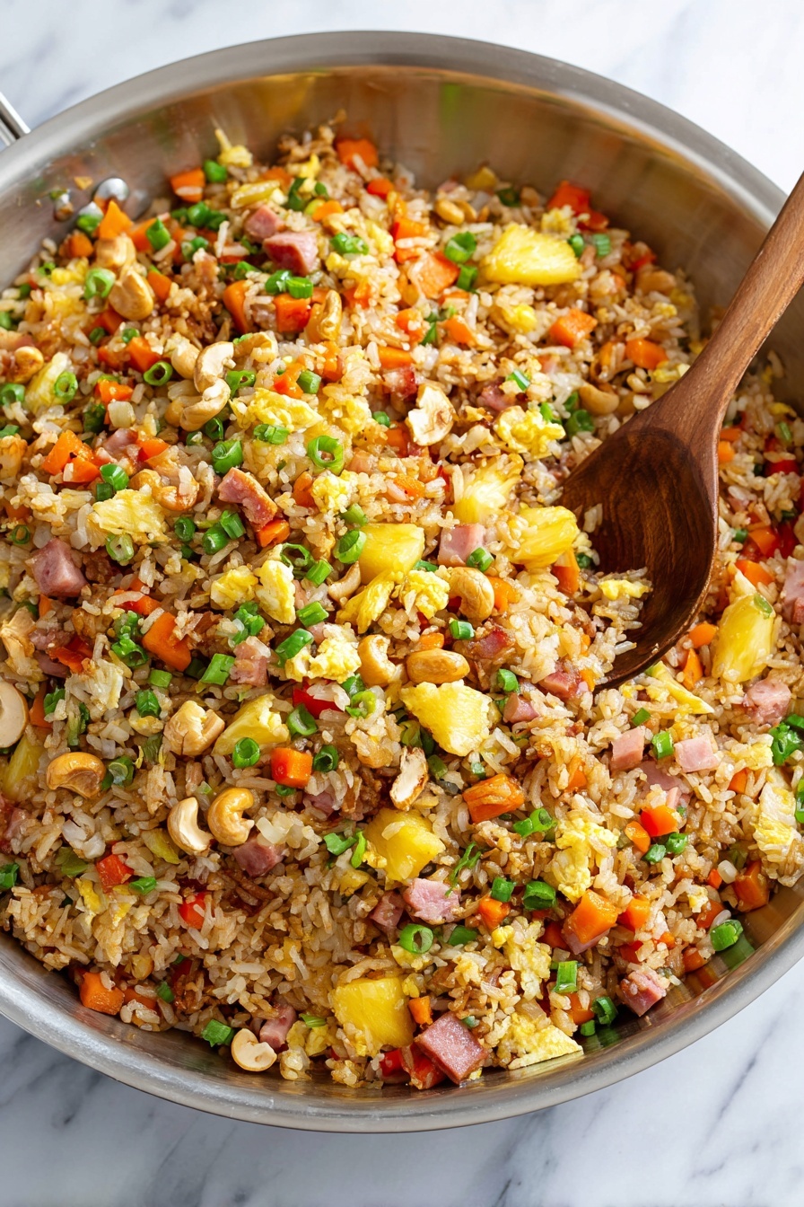 A large silver bowl filled with colorful fried rice mixed with small diced red bell peppers, orange carrot pieces, yellow scrambled egg bits, green chopped spring onions, and light yellow pineapple chunks. There are also scattered light brown cashew nuts and small pink ham cubes throughout. The grains of rice are brownish and look well-cooked with a slight shine. A silver spoon is partly dug into the rice, slightly lifting some of the mix. The bowl sits on a white marbled surface. photo taken with an iphone --ar 2:3 --v 7